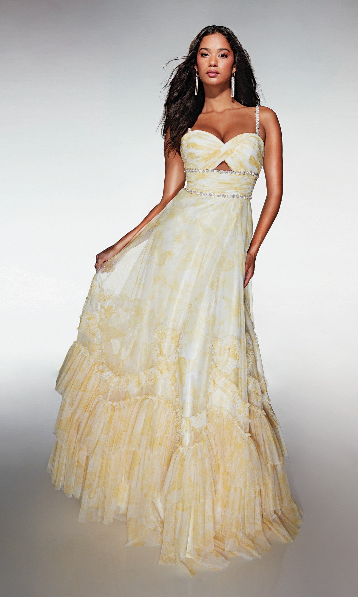 A woman in the Alyce 62063 long formal dress—yellow and white with spaghetti straps, a fitted bodice, and a flowing ruffled skirt—stands against a neutral background.